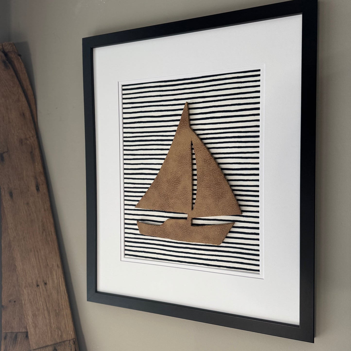 Black framed leather sailboat on a navy blue striped fabric background