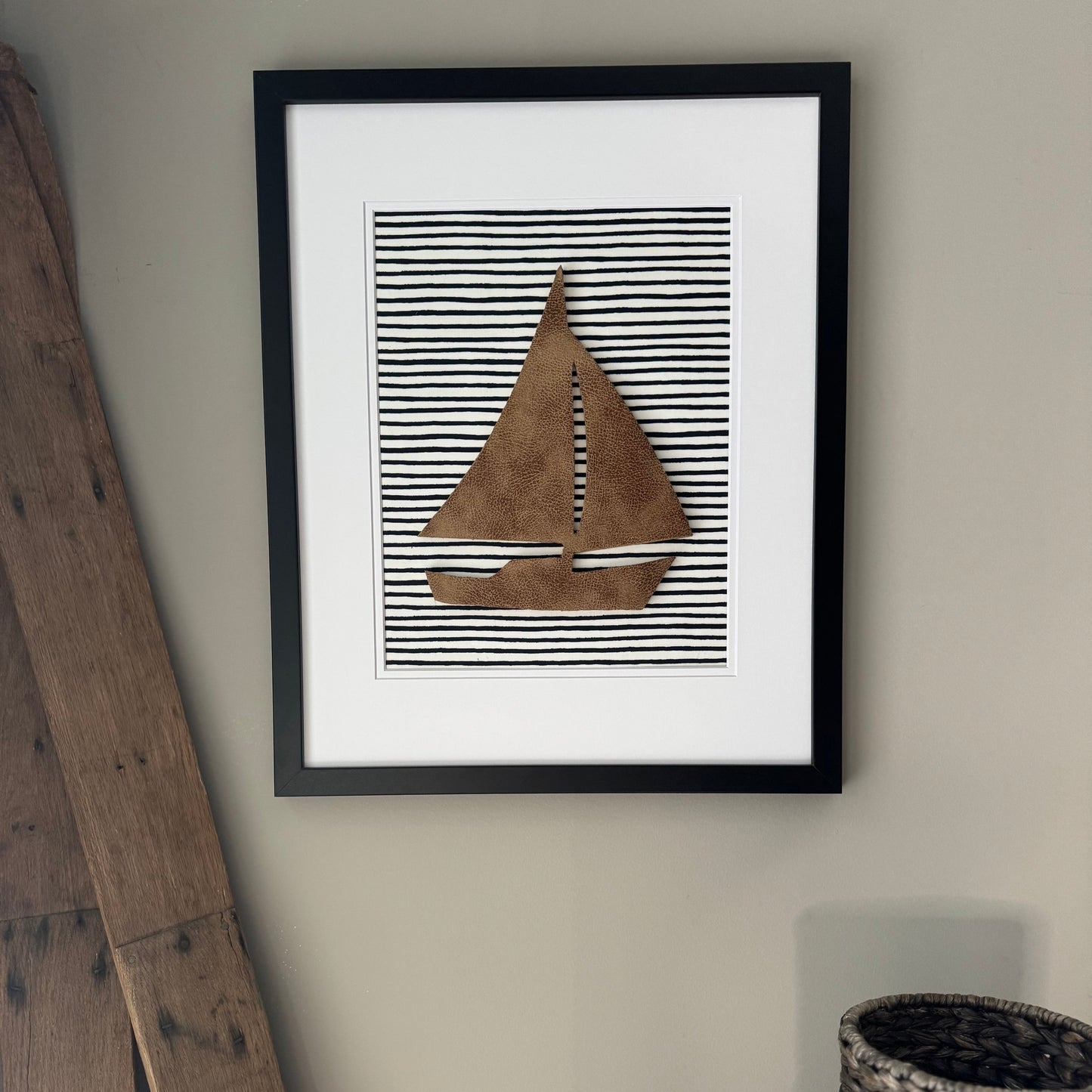 Black framed leather sailboat on a navy blue striped fabric background