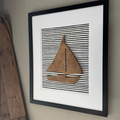 Black framed leather sailboat on a navy blue striped fabric background